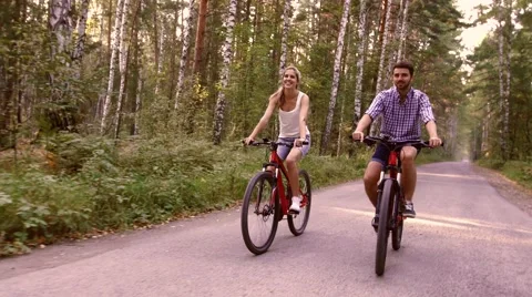 Portrait of happy couple having fun on bicycle ride in the summer park Видео 68059503