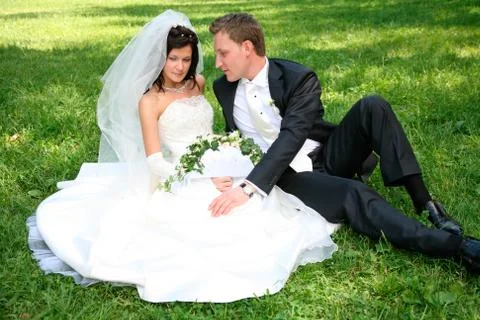 Portrait of happy couple sitting on the grass after marriage Stock Photos