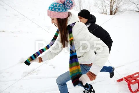 Portrait of happy couple in warm clothes running outdoors in winter Stock Photos
