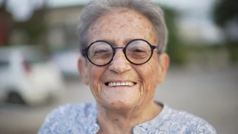 Portrait of happy elderly woman with black round glasses smiling. Stock Footage