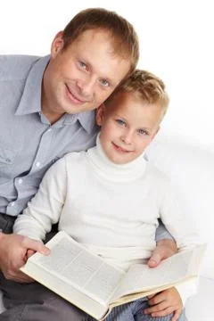 Portrait of happy father and son with open book looking at camera Stock Photos