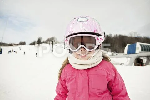 Portrait of happy girl in ski-wear on snow covered mountain Stock Photos