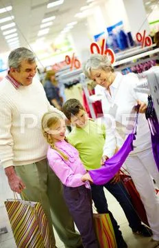 Portrait of happy grandparents and grandchildren choosing clothes in the mall Stock Photos