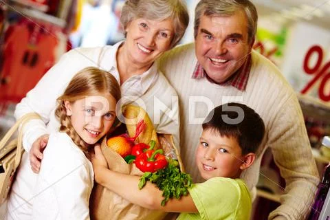 Portrait of happy grandparents and grandchildren holding package with food Stock Photos