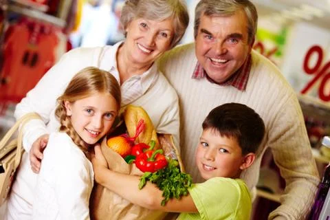 Portrait of happy grandparents and grandchildren holding package with food Stock Photos
