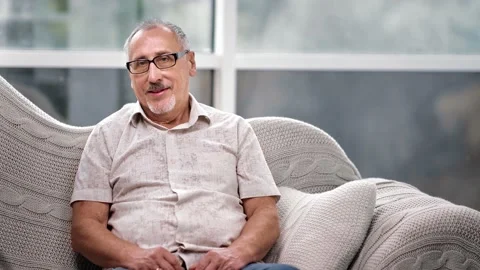 Portrait of happy gray haired elderly man smiling posing on couch. Shot with RED Stock Footage 143613502