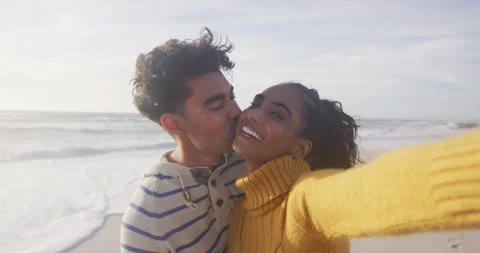 Portrait of happy hispanic couple standing on beach, taking selfie Stock Footage 342017656