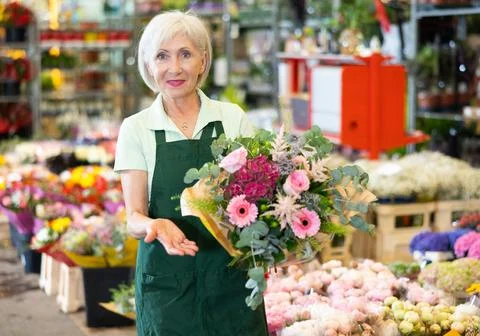 Portrait of happy hostess of flower market with bouquet in her hands Stock Photos