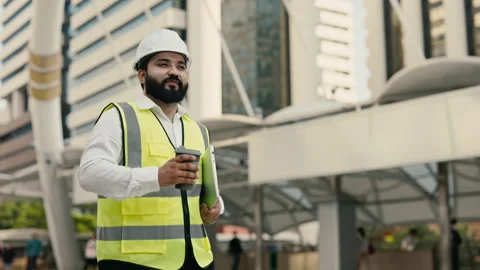 Portrait of happy Indian construction engineer with laptop drinking coffee Stock Footage 312473385
