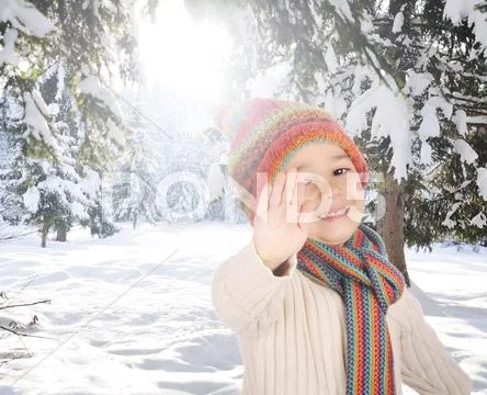 Portrait of happy kid wearing warm clothes in snow on a cold winter day, smil Stock Photos