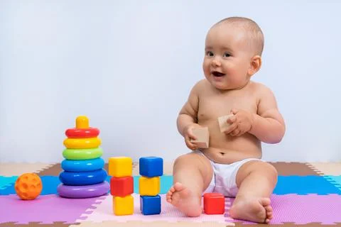 Portrait of happy laughing baby 8-12 months old in playroom on white backgrou Stock Photos