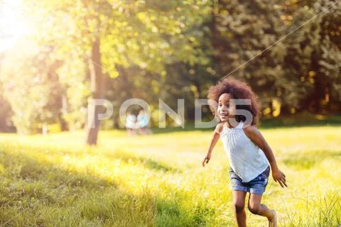 Portrait of happy little girl running on grass land Stock Photos