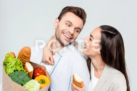 Portrait of happy man and woman with grocery bag looking at each other on whi Stock Photos