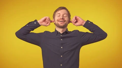 Portrait of happy man smiling at camera and plugging his ears with fingers Stock Footage 129336667