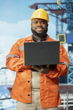 Portrait of happy offshore platform engineer using monitoring software on laptop Stock Photos