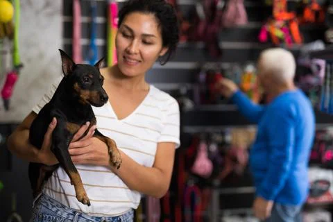 Portrait of happy positive woman visiting pet supplies store with dog doberman Stock Photos