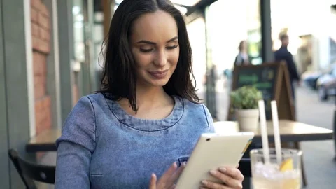 Portrait of happy, pretty woman with tablet sitting in cafe in city Stock Footage