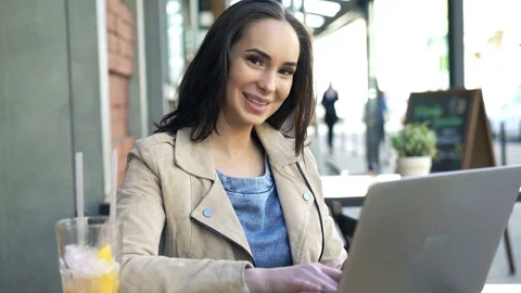 Portrait of happy, pretty woman using laptop in cafe in city Stock Footage