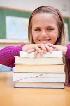 Portrait of a happy schoolgirl posing with a stack of books 스톡 사진