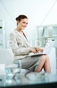 Portrait of happy secretary sitting in office and typing Stock Photos