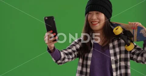Portrait of happy skater girl taking selfies with smartphone on green screen Stock Photos