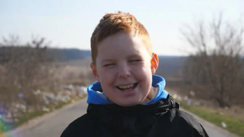 Portrait of happy smiling red-haired child in jacket looks into camera outdoor Stock Footage 300340147