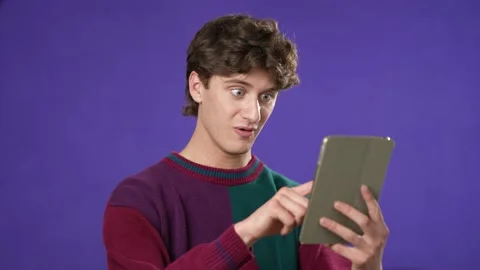 Portrait of happy smiling young guy 20s in sweater shopping on tablet computer Video stock 220934595