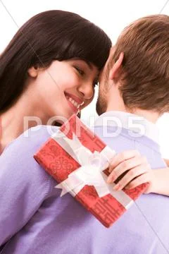 Portrait of happy woman looking at man with smile and keeping giftbox behind his Stock Photos