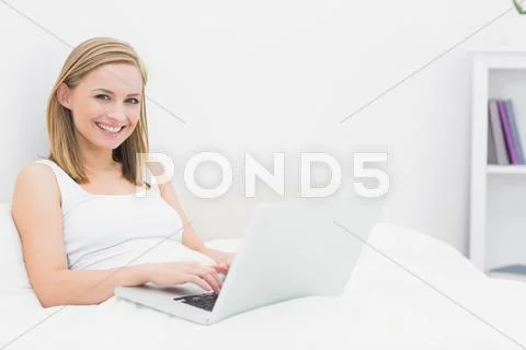 Portrait of happy woman using laptop in bed Stock Photos