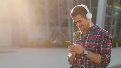 Portrait of a happy young man with a backpack listening to music on his Stock Footage 81047456