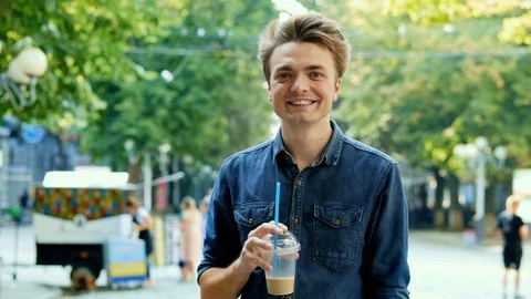 Portrait of happy young man drinks a cold cocktail on the city street Stock Footage 113231659