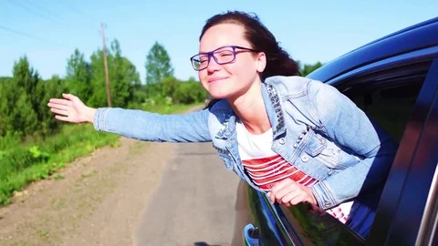 Portrait of happy young woman going on a road trip leaning out of window. Female Stock Footage