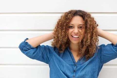 Portrait of a happy young woman smiling with hands in hair Stock Photos