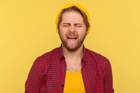 Portrait of hipster guy in beanie hat and checkered shirt making disobedient  Foto stock