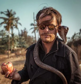 Portrait of hipster poet in trench coat with apple in the hand and cobra  Stock Photos