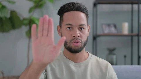 Portrait of Hispanic Man with Stop Gesture Sitting at Home Stockbeeldmateriaal 293258937