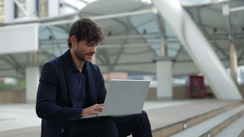Portrait of Hispanic office worker smiles and uses laptop on step in city center Stock Footage 311802176