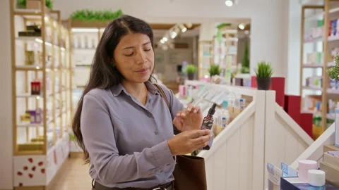 Portrait of Hispanic Woman Testing Face Serum in Cosmetics Store Stock Footage 345521592