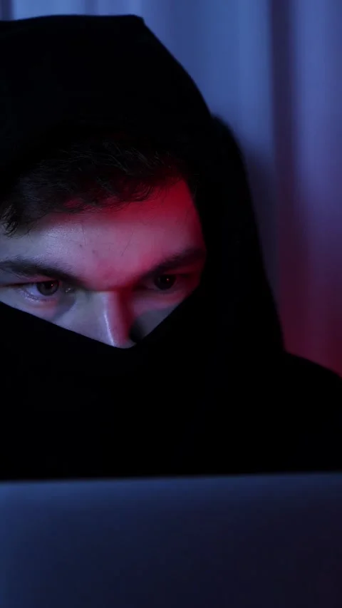 Portrait of hooded hacker programming on laptop in dark room. Vertical video Stock Footage 318162627