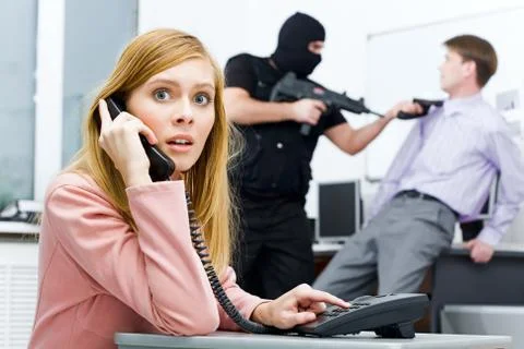 Portrait of horrified businesswoman pushing buttons of telephone while terrorist Stock Photos