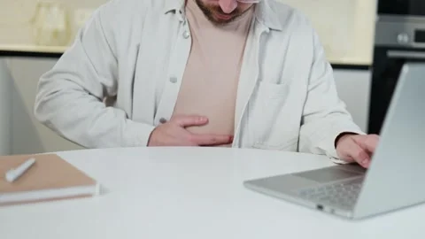 Portrait of ill man looking at computer screen and putting hand on stomach Stock Footage 266895268