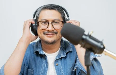 Portrait image of a cheerful middle-aged man with glasses holding headphone Stock Photos