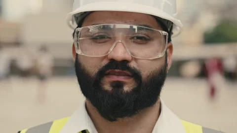 Portrait of Indian builder with protective goggles standing at construction site Video stock 311932930