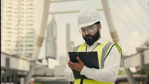 Portrait of Indian engineer with goggles and safety vest holding clipboard Stock Footage 312473448