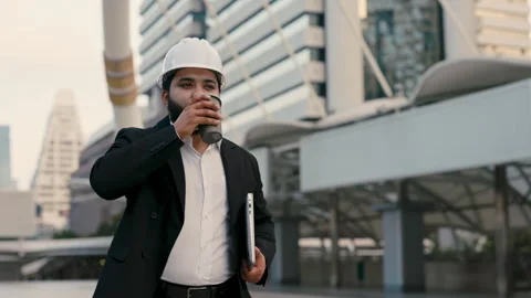 Portrait of Indian engineer with helmet with coffee and laptop by buildings Stock Footage 311065652