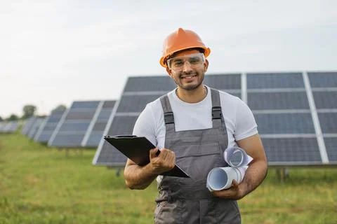 Portrait of indian engineer in uniform posing at solar farm Stock Photos