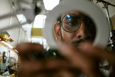 Portrait of Indian Man Inspecting Electronics with Magnifier 스톡 사진