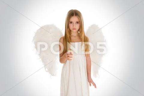 Portrait of innocent girl with candle and wings surrounded by holy light looking Stock Photos