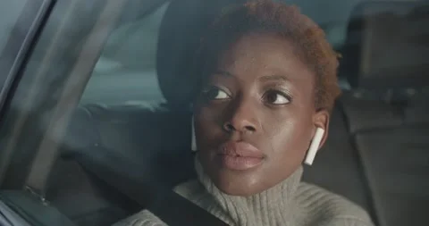 Portrait inside moving car of a young black woman traveling with her earphones Stock Footage 186005978
