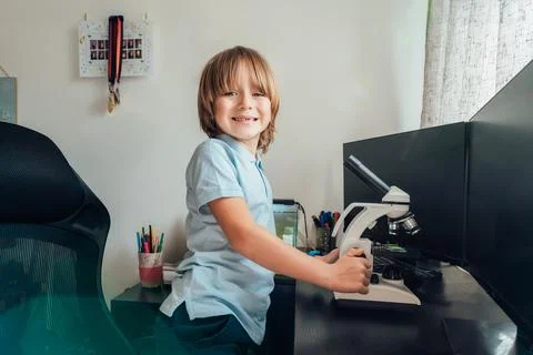 Portrait of inspired Caucasian boy using a microscope at home at his study place Stock Photos